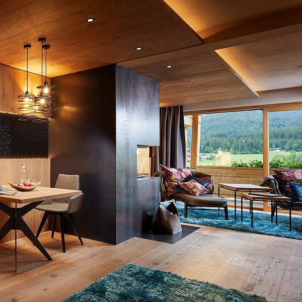 Wohnzimmer mit kleinem Tisch und stühlen, Kamin mit Sichtfenster, Couch und großem Panoramafenster