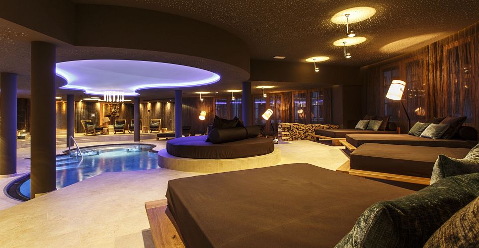 Ein luxuriöser Spa-Bereich mit Liegen und einem kleinen Pool, umgeben von sanfter Beleuchtung und gemütlicher Atmosphäre.
