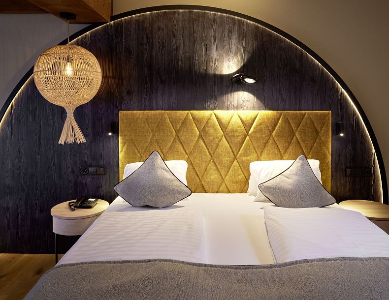 Gemütliches Doppelbett mit Boho Hängelampe an der Seite und angenehmer indirekter Beleuchtung