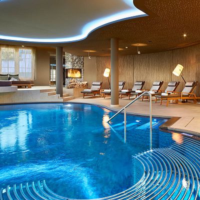 Geschwungener Pool in elegantem Wellnessbereich mit bequemen Liegen im Hintergrund