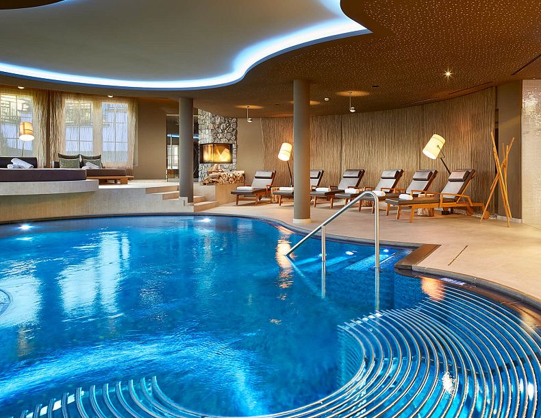 Geschwungener Pool in elegantem Wellnessbereich mit bequemen Liegen im Hintergrund