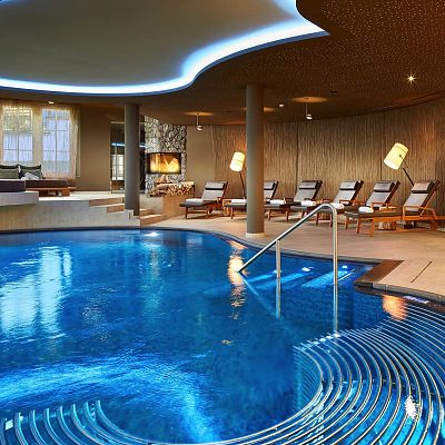 Geschwungener Pool in elegantem Wellnessbereich mit bequemen Liegen im Hintergrund
