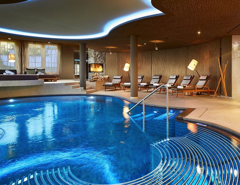 Geschwungener Pool in elegantem Wellnessbereich mit bequemen Liegen im Hintergrund