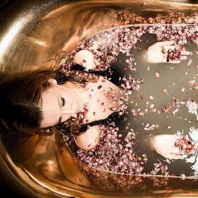 Dame badet in eleganter Wanne mit Rosenblättern