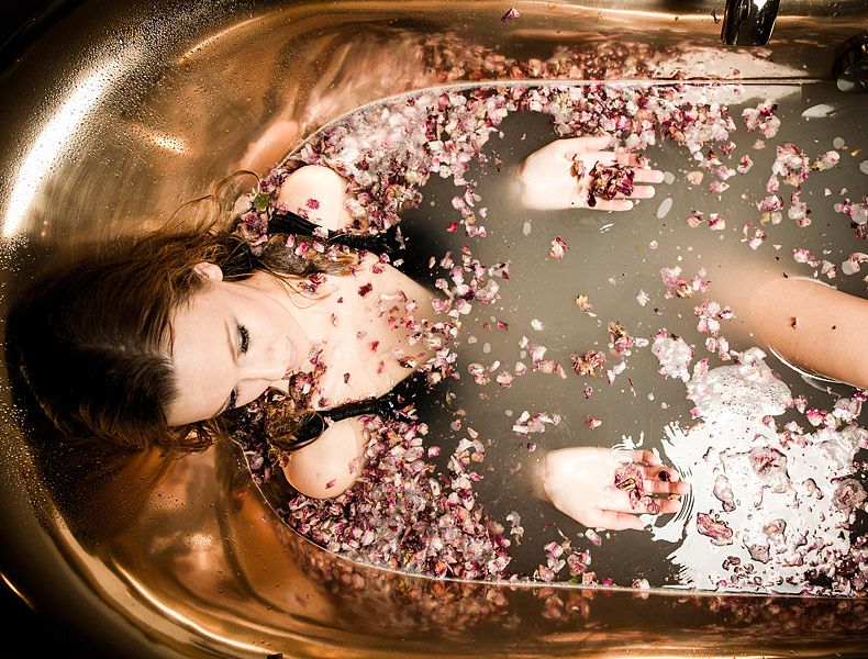Dame badet in eleganter Wanne mit Rosenblättern